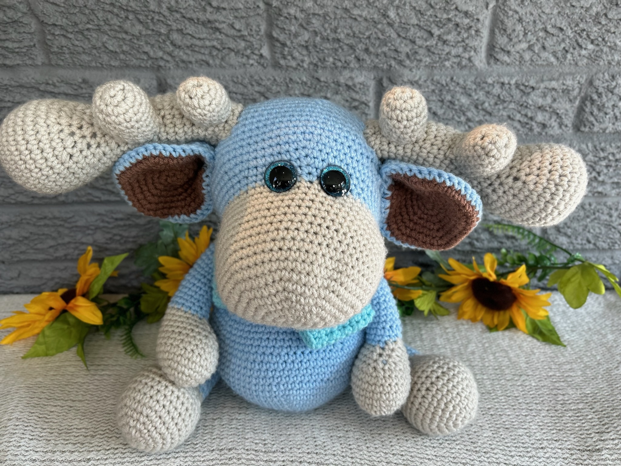 photo of crocheted moose, with a blue body and bright blue bow