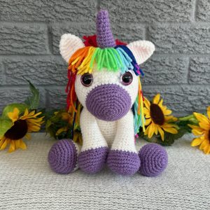 Photo of a crocheted unicorn with purple accents and rainbow mane