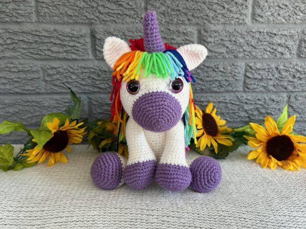 Photo of a crocheted unicorn with purple accents and rainbow mane