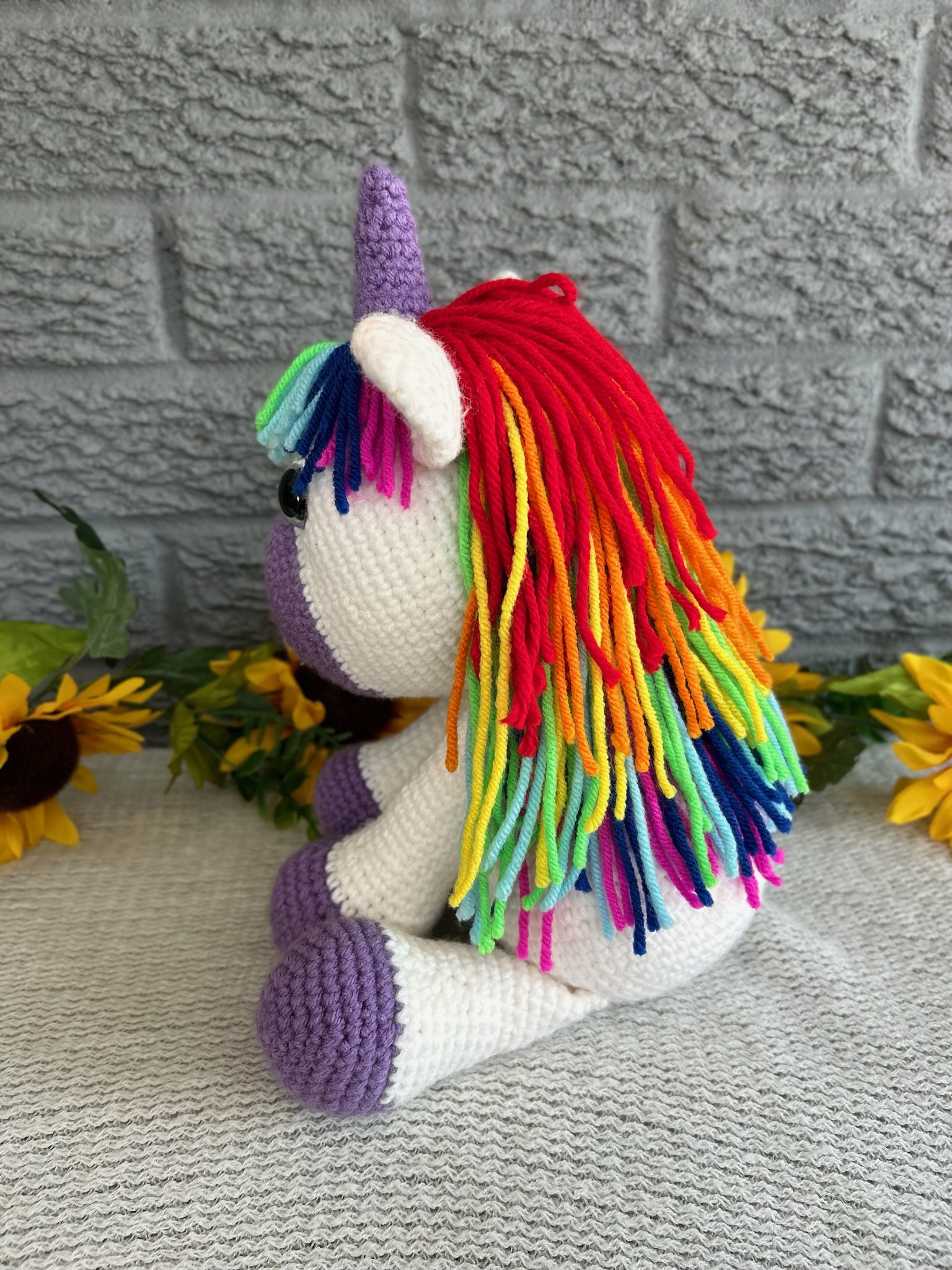 Photo of a crocheted unicorn with purple accents and rainbow mane