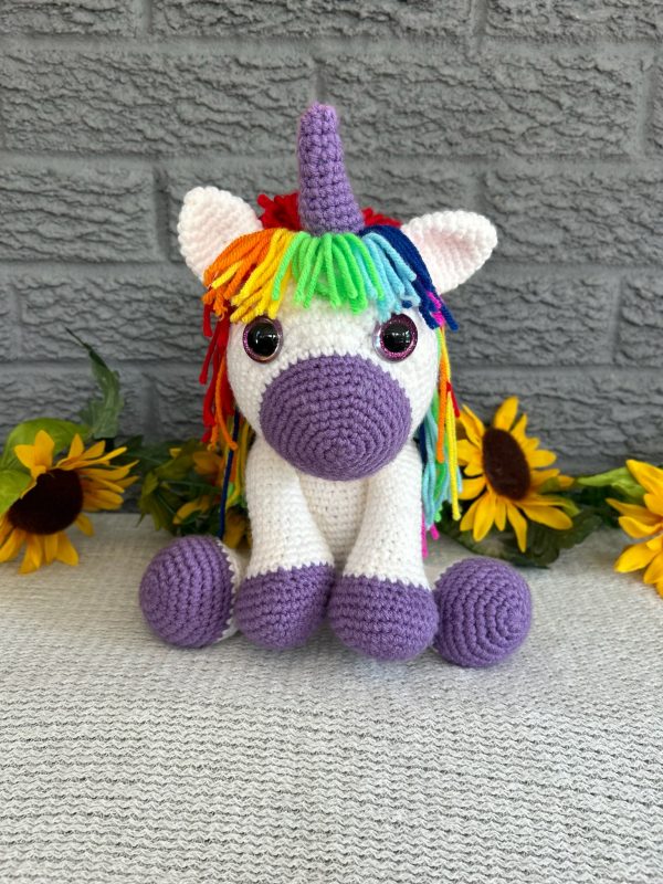 Photo of a crocheted unicorn with purple accents and rainbow mane