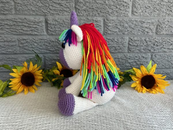 Photo of a crocheted unicorn with purple accents and rainbow mane