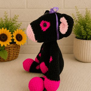 Side-crocheted-pink-cow Image Jul 4, 2026, 12_01_08 AM Side profile of handmade crochet black and pink cow plush with purple ribbon.