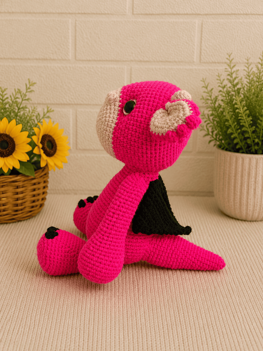 Side profile of handmade crochet pink dragon plush facing right