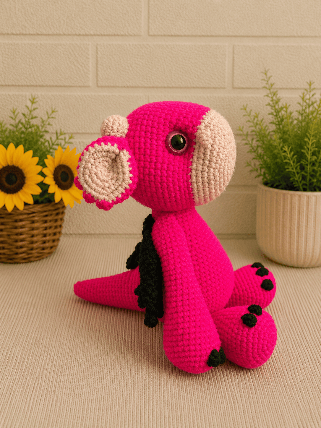 Side profile of handmade crochet pink dragon plush facing left