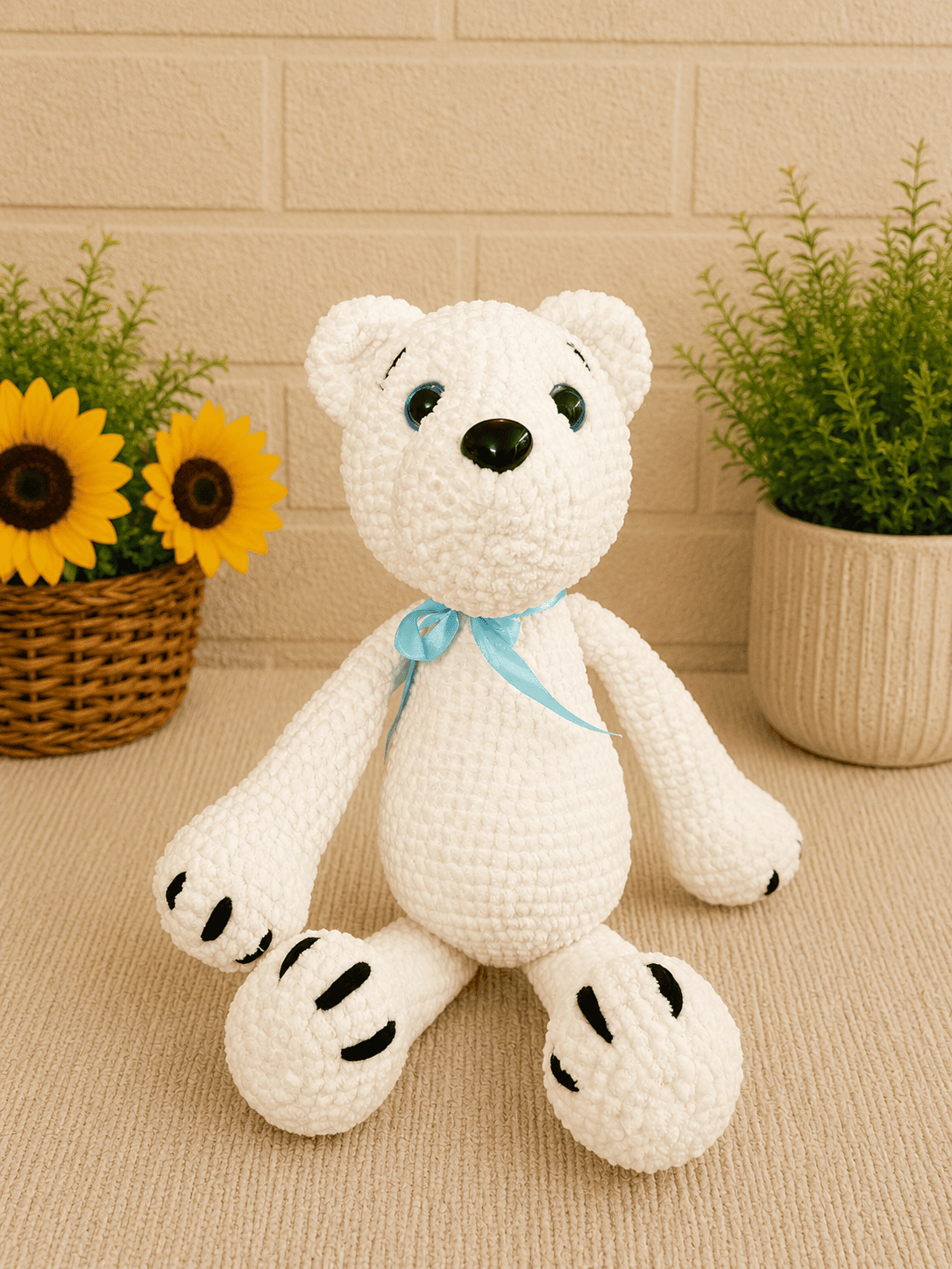 Handmade crochet polar bear sitting with blue ribbon.